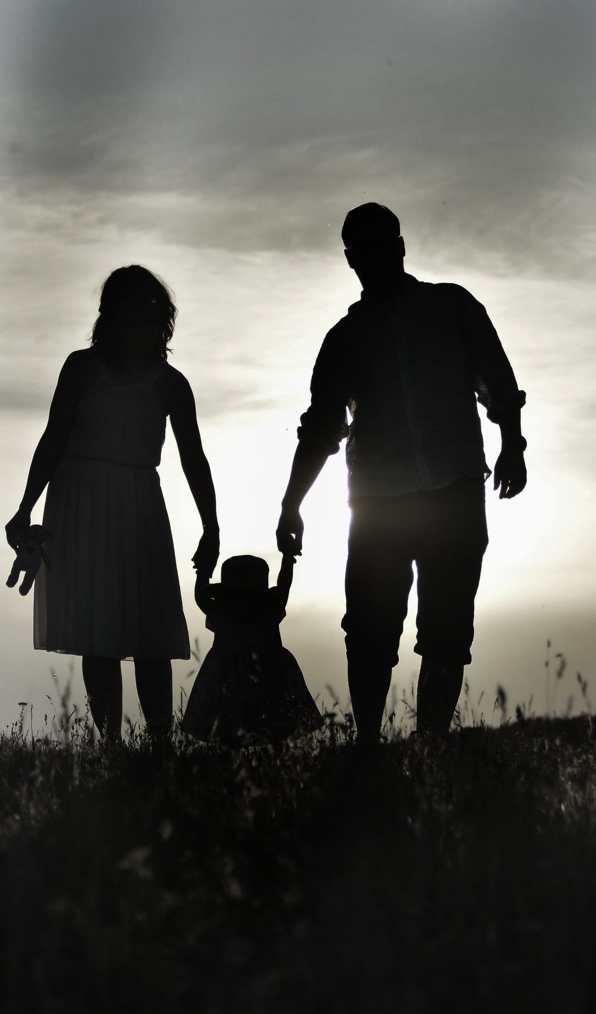 Siluetă de familie cu un copil, fotografiată în contralumină la apus — MC Photography, Craiova
